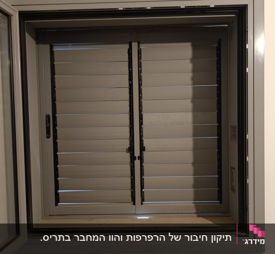 חלון עם תריסים סגורים על קיר לבן